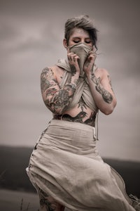 a woman in a white dress with tattoos on her face