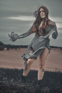 a woman in a gray dress standing in a field