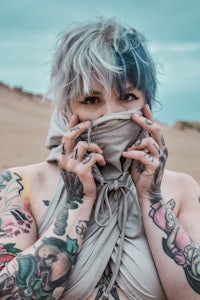 a woman with tattoos covering her face in the desert