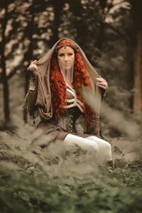 a red haired woman sitting in the woods