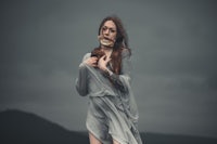 a woman in a long dress standing on a hill