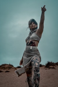 a woman with tattoos standing in the desert