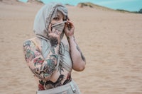 a woman with tattoos standing in the sand