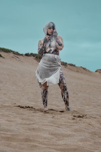 a woman in a white dress standing on a sand dune