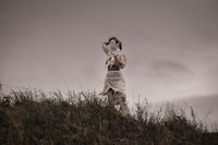 a woman in a white dress standing on a hill