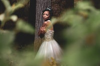 a black woman in a wedding dress in the woods