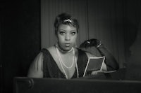 a black and white photo of a woman sitting at a piano