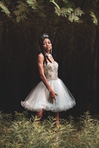 a woman in a white dress posing in the woods