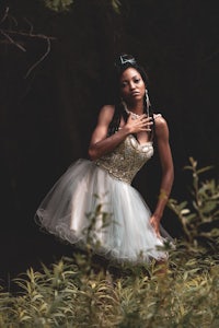 a black woman in a white dress posing in the woods