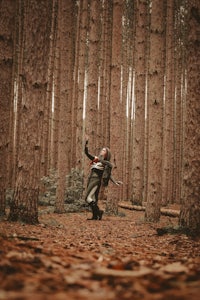 a man running through a forest with a bow and arrow