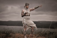 a woman with tattoos standing on top of a hill