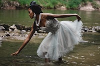 a woman in a white dress standing in a river