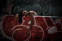 a woman leaning against a wall covered in graffiti