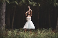 a woman in a white dress in the woods