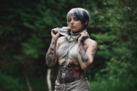 a woman with tattoos posing in the woods